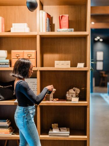 a woman is reaching into a book shelf at The Junto Hotel in Columbus