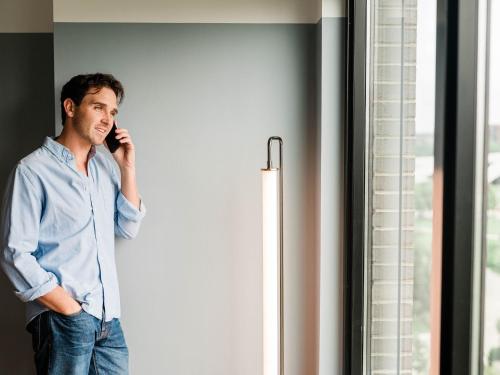 a man talking on a cell phone next to a window at The Junto Hotel in Columbus