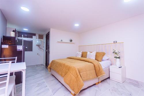 a bedroom with a bed and a desk and a kitchen at Comuna Loft in Medellín