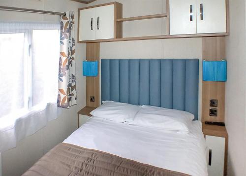 a bed with a blue headboard in a bedroom at Stanwix Park in Silloth