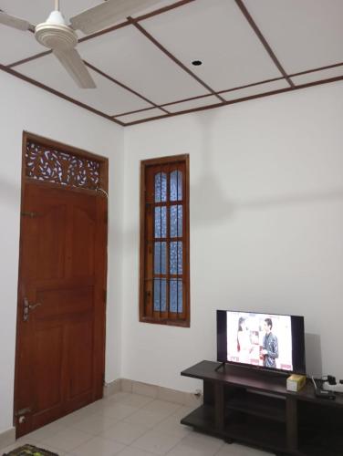 a living room with a tv and a door at Green Terrace Homestay 