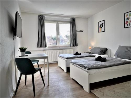 a bedroom with two beds and a desk and a table at Work Inn Rhein Ruhr Appartement in Duisburg