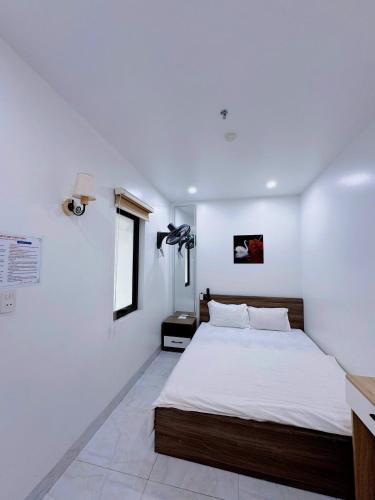 a bedroom with a bed with white walls and a window at Lake View Hotel in Cat Ba
