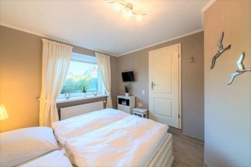 a bedroom with two beds and a window at Strandgut EG in Morsum