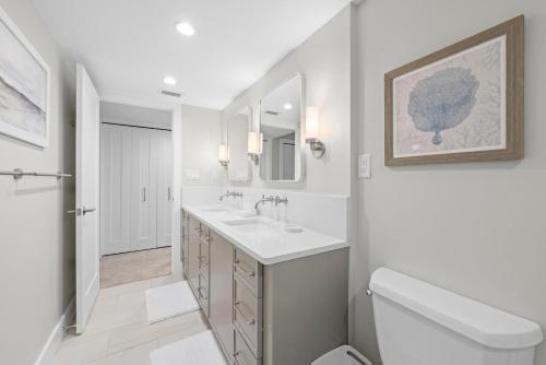 Baño blanco con 2 lavabos y aseo en Sundial T405, en James Cipriani Heliport