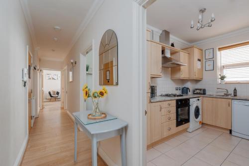 a kitchen with a vase of flowers on a table at Ocean Spray Suite by Grandeur Property in Bournemouth