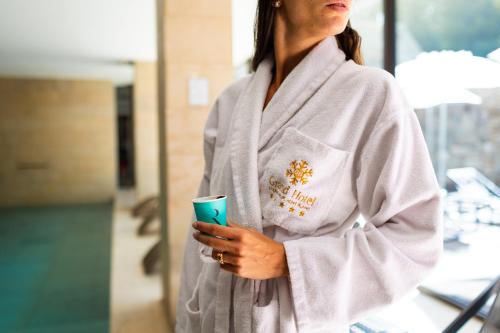 a woman in a bathrobe holding a cup of coffee at Grand Hotel Courmayeur Mont Blanc, by R Collection Hotels in Courmayeur