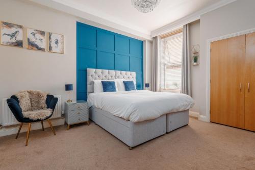 a bedroom with a large bed with a blue wall at Ocean Spray Suite by Grandeur Property in Bournemouth