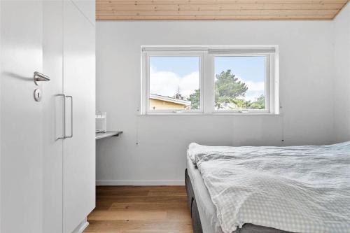 a white bedroom with a bed and a window at N312-Karrebaeksminde-Cypresvaenget-43 in Enø By