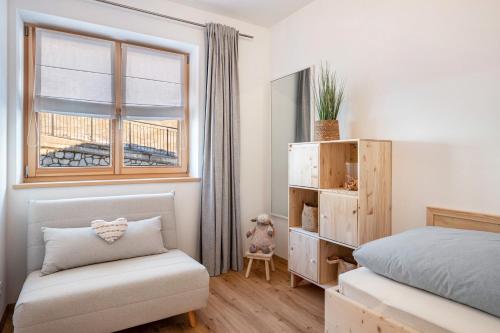 a bedroom with a bed and a window and a chair at Jan's Apartment am See in Pracupola