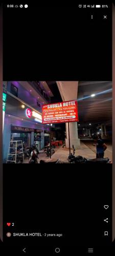 a sign for a hotel with motorcycles parked in a parking lot at Shukla Hotel in Kānpur