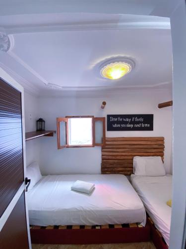 two beds in a small room with a window at Imsouane soul lodge in Imsouane
