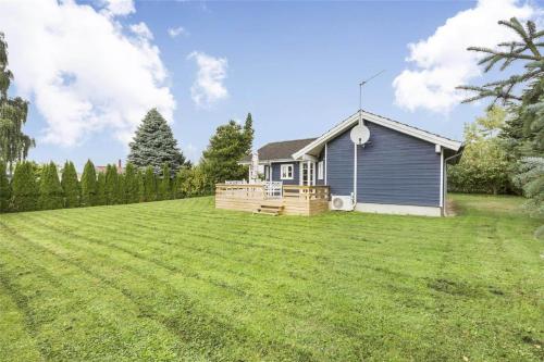 a small blue house on a large grass field at N106-Karrebaeksminde-Krageholmsvej-97 in Enø By