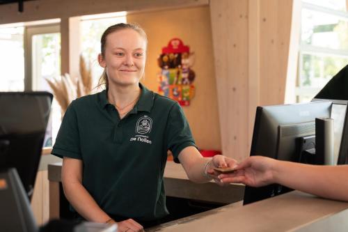a woman in a green shirt is shaking hands at Chalet 4 personen in Callantsoog