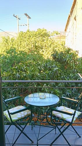 a table and chairs on a balcony with a hedge at Skardamoula's Studios n Apartments in Kardamili