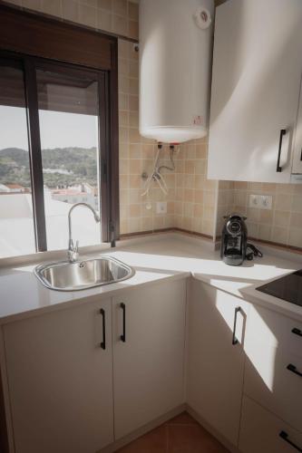 a kitchen with a sink and a window at Suites Neade Residencial in Sanlúcar de Guadiana