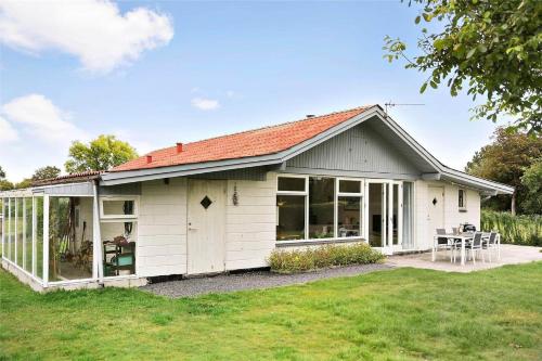 a white shed with a table and chairs in a yard at N242-Karrebaeksminde-Kildeengen-44 in Enø By