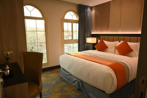 a bedroom with a bed with orange pillows and two windows at فندق امان أبها - المعالي in Abha