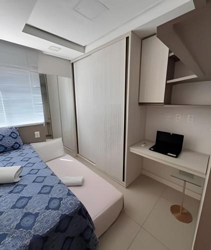 a bedroom with a bed and a desk with a laptop at Oásis próx à Novafapi in Teresina