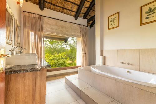 ein Badezimmer mit Badewanne und Waschbecken und einem Fenster in der Unterkunft Waterberg House at Zebula - 8 adults and 4 kids under 10 years in Mabula