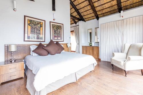 ein Schlafzimmer mit einem weißen Bett und einem Stuhl in der Unterkunft Waterberg House at Zebula - 8 adults and 4 kids under 10 years in Mabula
