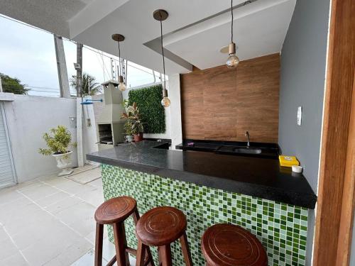 una cucina con bancone, sgabelli e lavandino di Casa por temporada trapiche Maceió Alagoas a Maceió