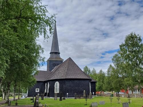 a church with a tall steeple on a cemetery at Centrally located holiday home in Stöllet in Stöllet