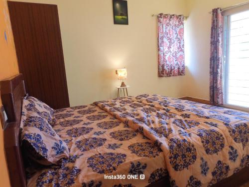 a bedroom with a bed with a comforter and a window at AAK Hills stay villa in Kodaikānāl