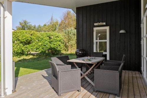 a patio with a table and chairs on a deck at JB241-Fjerritslev-Lyngstien-25 in Torup Strand