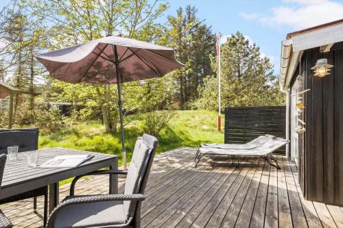 a patio with an umbrella and a table and chairs at JB323-Fjerritslev-Markstien-21 in Torup Strand