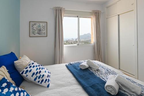 a bedroom with a bed with blue pillows and a window at Casa BuenaVista Calpe in Casas de Torrat