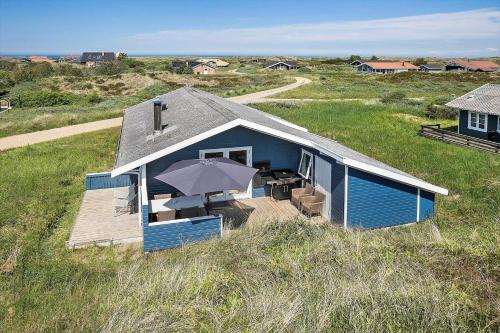 a blue house with an umbrella in a field at JB183-Frostrup-Svenstibakkevej-70 in Lild Strand
