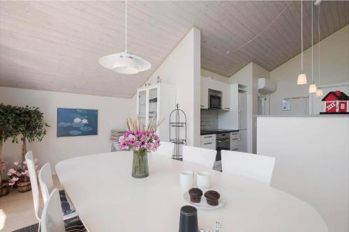 a white dining room table with white chairs and a vase of flowers at JB326-Brovst-Kronvildtvej-134 in Tranum