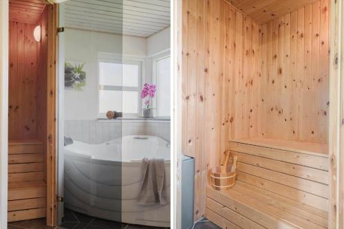 a bathroom with a tub in a wooden wall at JB326-Brovst-Kronvildtvej-134 in Tranum