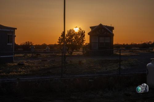 a sunset over a field with a fence and a building at 060A Brand New Cozy Cabin with Loft & King bed near Grand Canyon South Rim in Valle