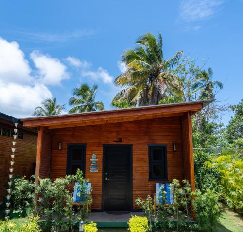 a wooden house with a palm tree in the background at Villa Dulce Refugio in Cabrera