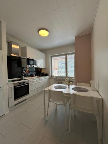 a white kitchen with a table and chairs in it at Beautiful two-room apartment with balcony in a prime location in Turku