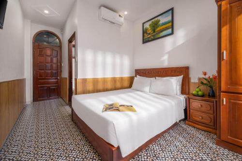 a bedroom with a bed with a book on it at Sala Hoi An Hotel in Hoi An