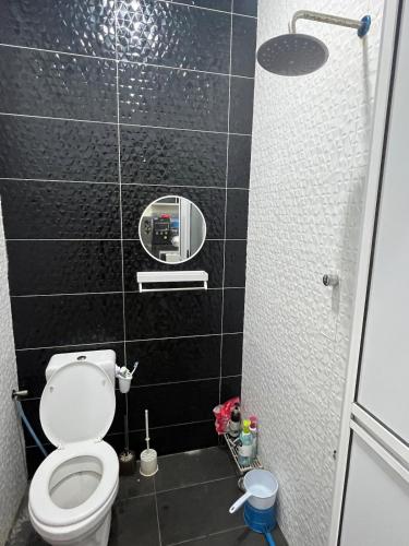 a bathroom with a toilet and a black tile wall at CozyInn Homestay 4 in Kampong Lanjut Manis