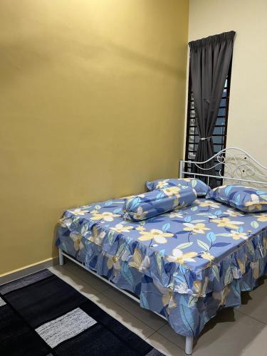 a bedroom with a bed with a blue and yellow comforter at CozyInn Homestay 4 in Kampong Lanjut Manis
