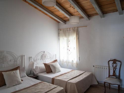 ein Schlafzimmer mit zwei Betten, einem Stuhl und einem Fenster in der Unterkunft CORTIJO EL PRADO ll in Castril