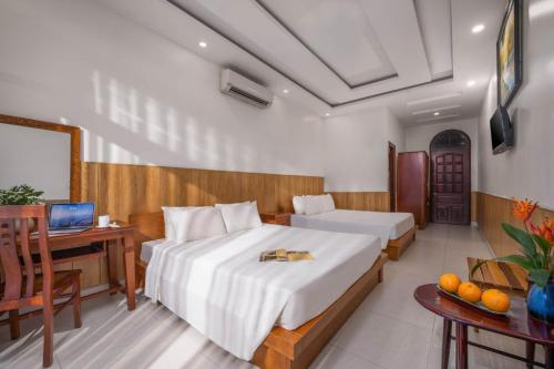 a bedroom with two beds and a desk with a computer at Sala Hoi An Hotel in Hoi An