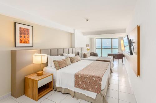 a bedroom with a large bed and a desk at HY Apartaments & Hotels-Boa Viagem in Recife