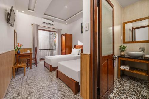 a hotel room with two beds and a sink at Sala Hoi An Hotel in Hoi An