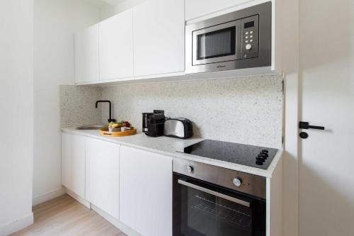a kitchen with white cabinets and a microwave at Résidence Saint Charles - Paris Expo in Paris