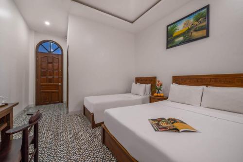 a hotel room with two beds and a door at Sala Hoi An Hotel in Hoi An