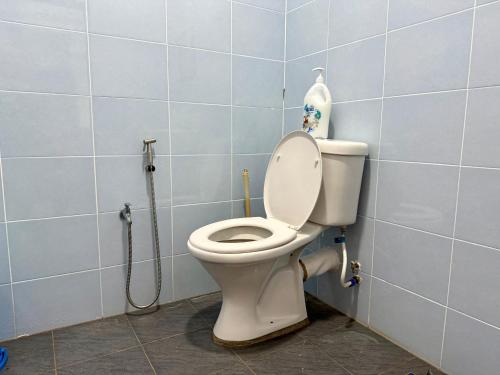 a bathroom with a toilet in a blue tiled wall at AL-REZQI RoomStay in Marang