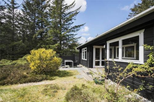 a black house with a white window and a yard at JB988-Fjerritslev-Skovstien-6 in Torup Strand