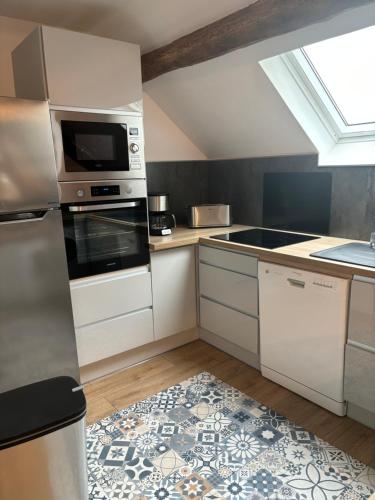 Dun-les-PlacesにあるMaison des tilleulsの白いキャビネットとコンロ付きオーブンを備えたキッチン