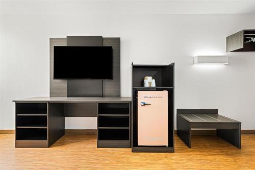 a room with a desk with a tv and a stand at Signature Inn Miami in Miami